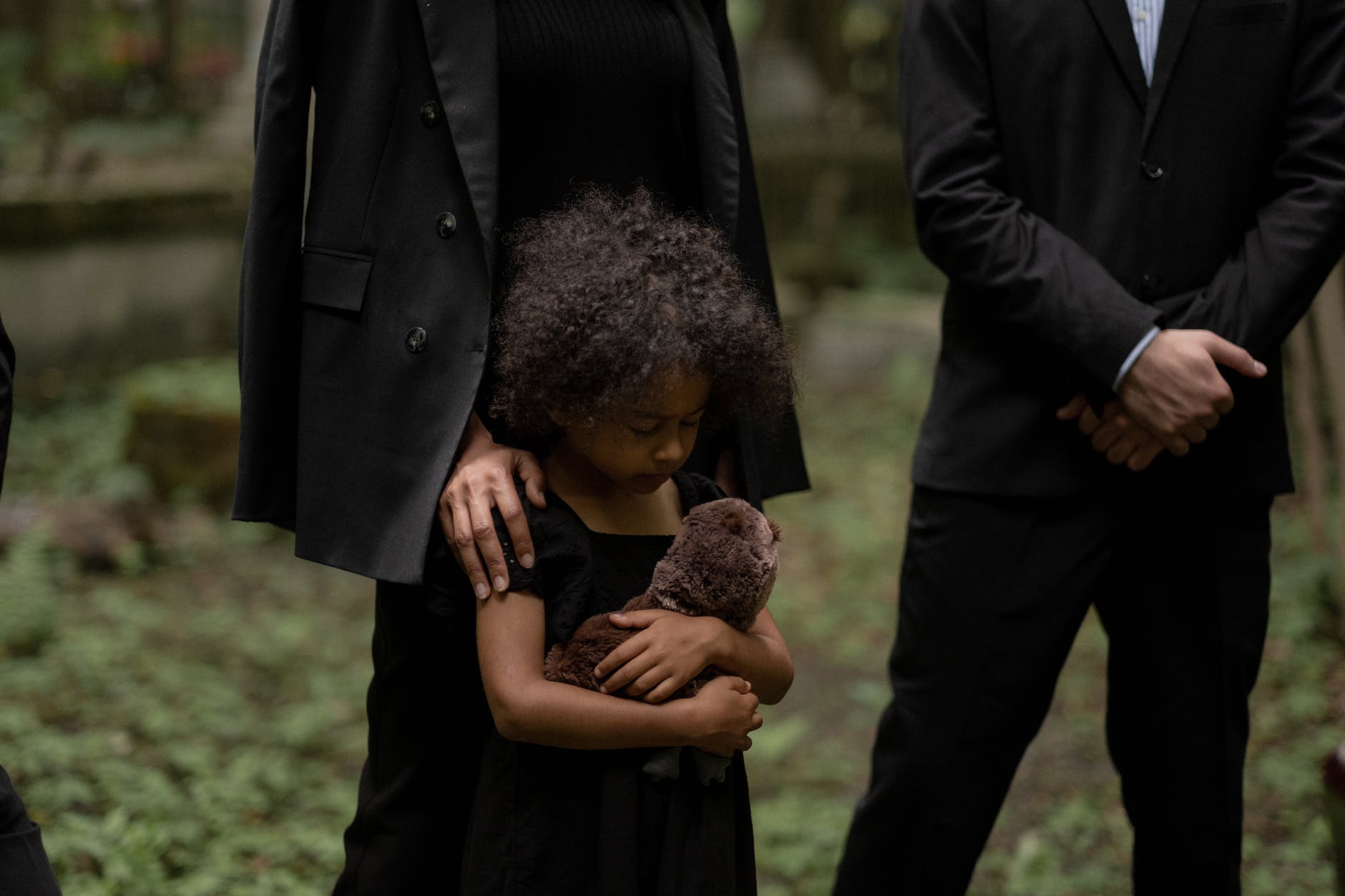 a young girl in black dress grieving in the cemetery