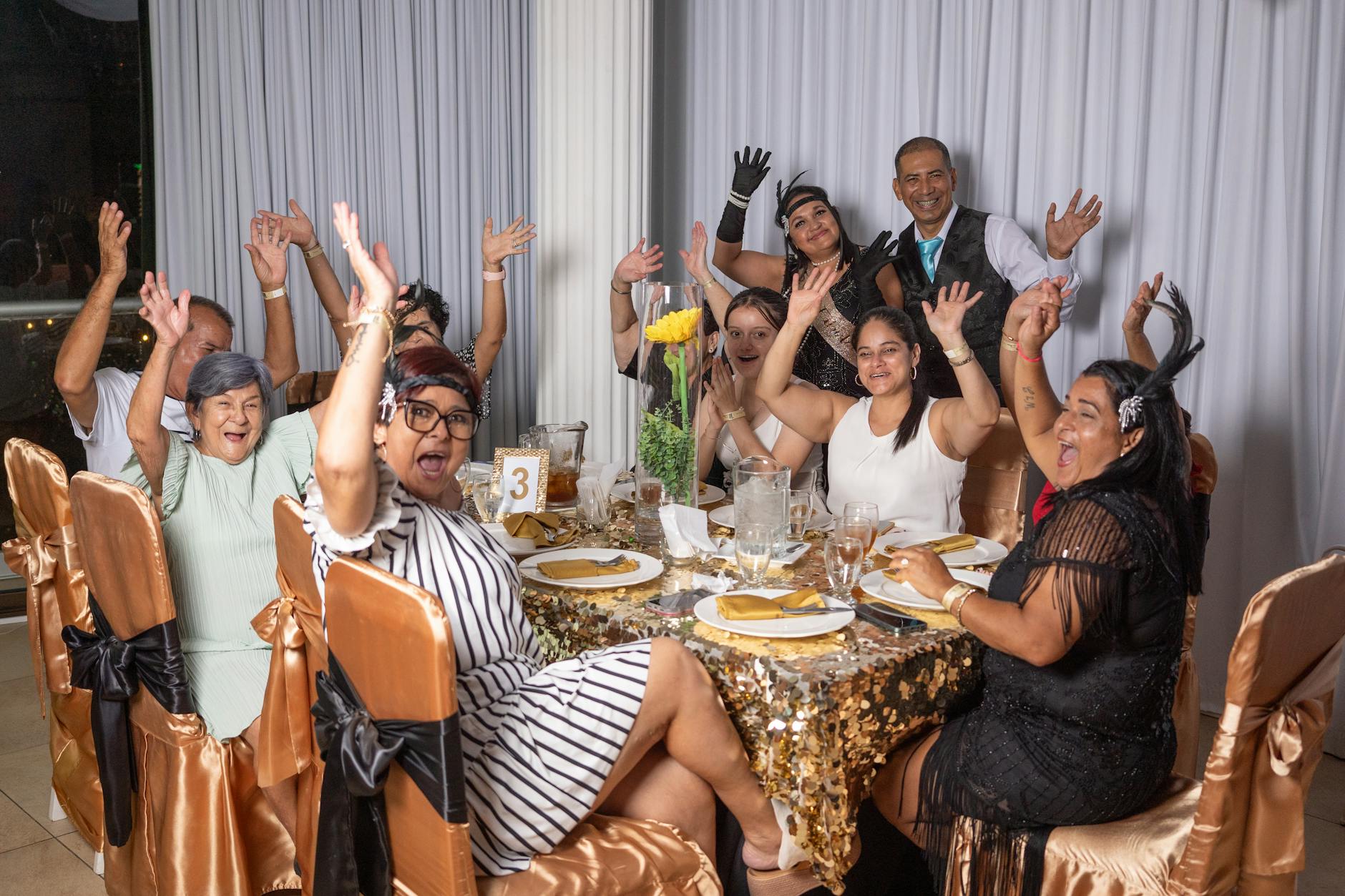 family sitting at a table at a birthday party waving at the camera