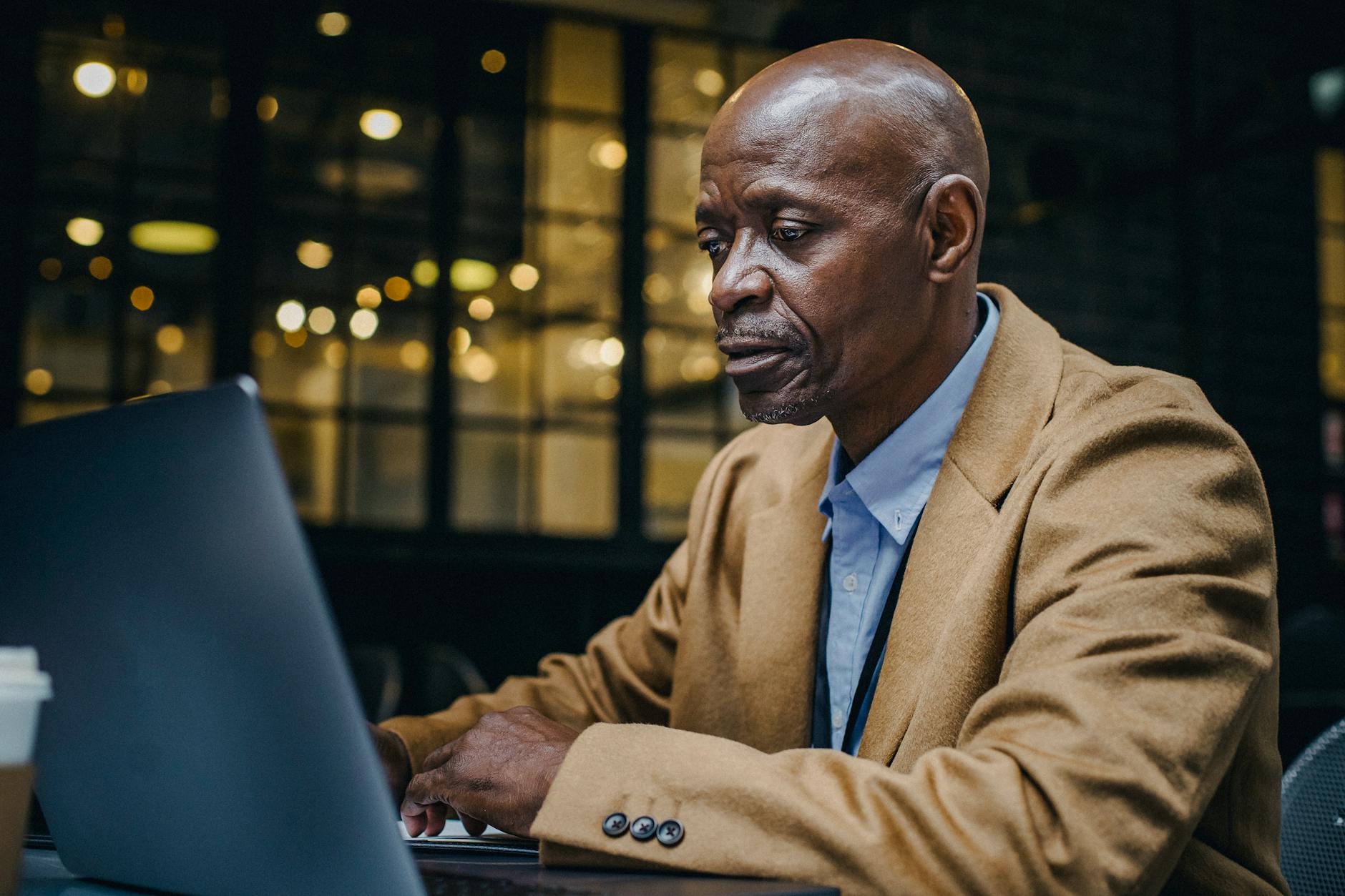 concentrated black entrepreneur working on laptop in coffee shop