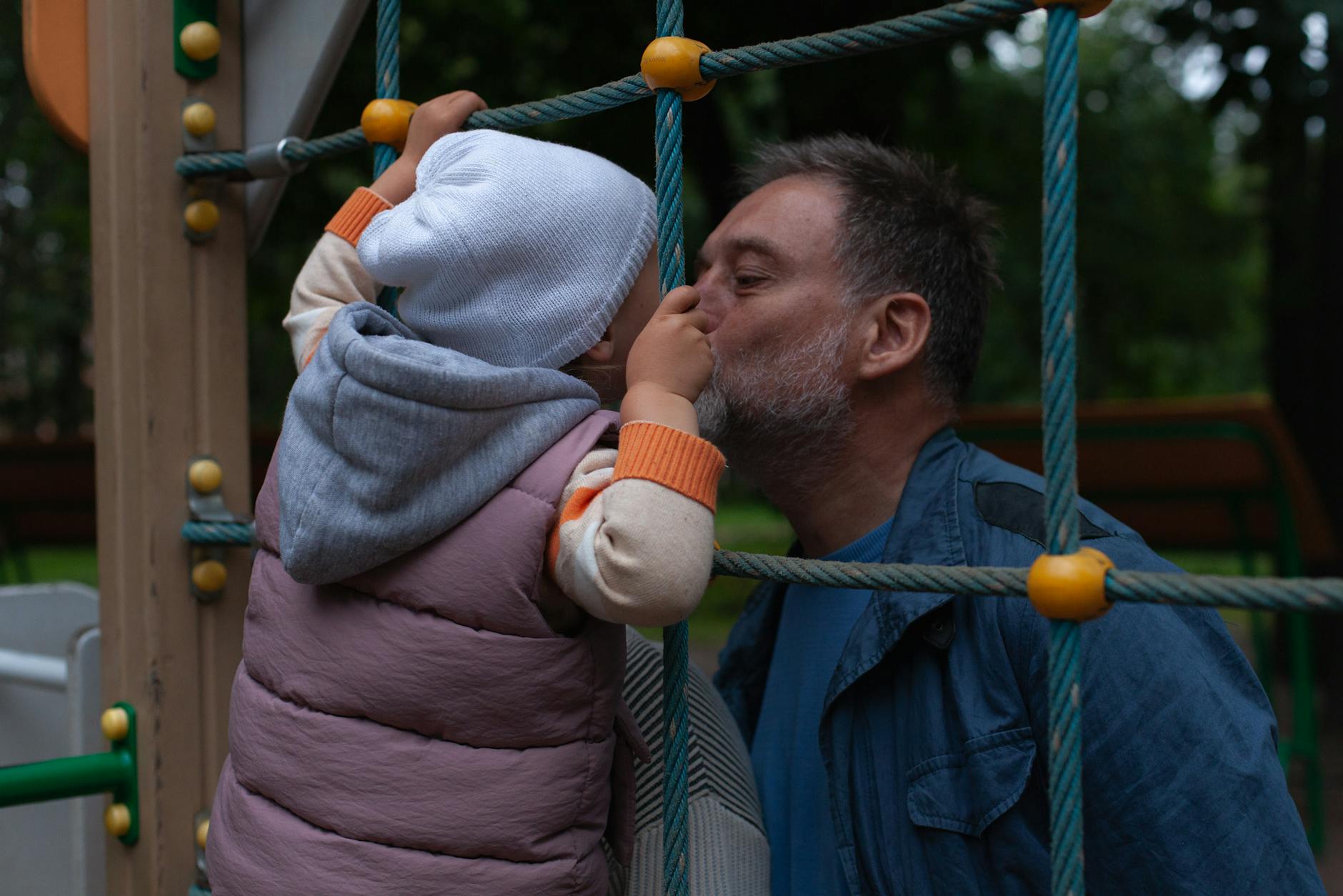 grandfather kissing grandchild on playground